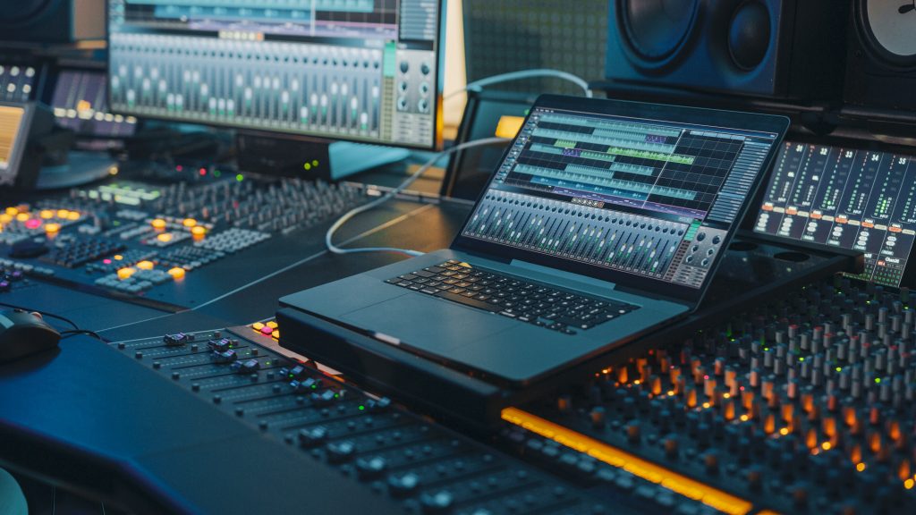 Modern Music Record Studio Control Desk with Laptop Screen Showing User Interface of Digital Audio Workstation Software. Equalizer, Mixer and Professional Equipment. Faders, Sliders. Record. Close-up – Foto- Adobe-Gorodenkoff